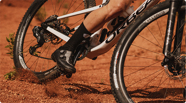 Detalle de una bicicleta de montaña en acción sobre terreno arenoso, mostrando los tipos de aros de bicicleta específicos para MTB que utiliza, optimizados para la tracción y estabilidad en Speedsix México.