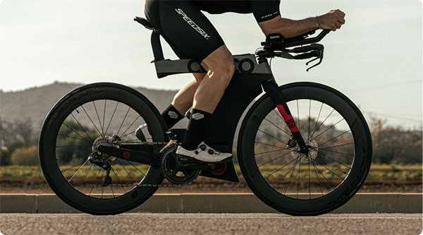 Ciclista en una bicicleta de ruta equipada con aros aerodinámicos, rodando por una carretera. La imagen resalta los tipos de aros de bicicleta utilizados, mostrando el diseño y el material de los aros de carbono que mejoran el rendimiento en Speedsix México.